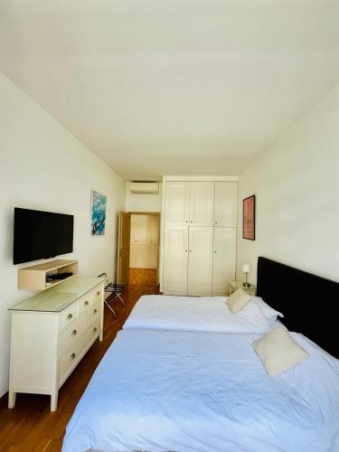 - une chambre avec un lit blanc, un bureau et une télévision dans l'établissement Golden Triangle 2Br/2Ba, à Cannes