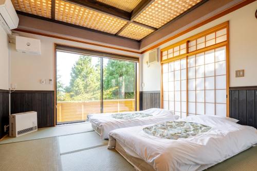 two beds in a room with a large window at 箱根御泊処-TOGA- 045h in Hakone