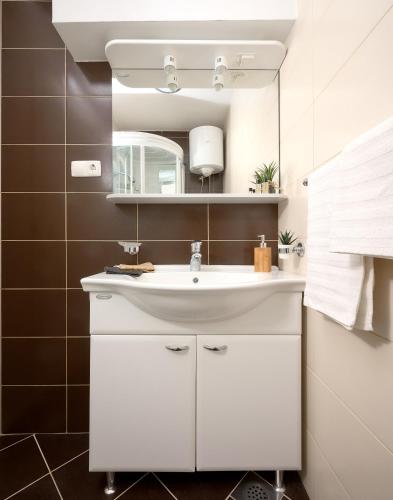 a bathroom with a white sink and a mirror at Sun Spalato Maslinica in Maslinica