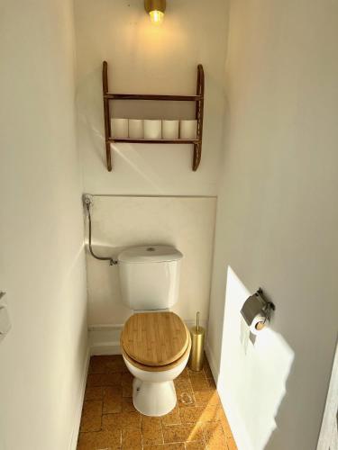 La salle de bains est pourvue de toilettes et d'un siège en bois. dans l'établissement Charmant appartement 3 chambres à 100m de la plage centrale, à Canet