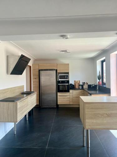 une cuisine avec des armoires en bois et un réfrigérateur en acier inoxydable dans l'établissement Penthouse Sanctuaire à Lourdes, à Lourdes