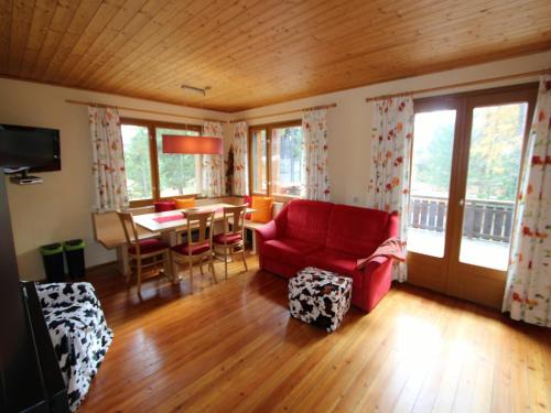 salon z czerwoną kanapą i stołem w obiekcie Sunlit Cabin with Jacuzzi in Turracherhohe w mieście Turracher Hohe