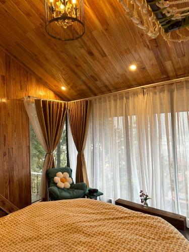 a bedroom with a bed and a chair and windows at Gio Homestay & Bungalow Sapa in Sa Pa