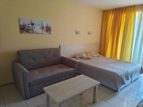 a bedroom with a bed and a couch and a table at Daisy Studios Harmony Hills in Rogachevo