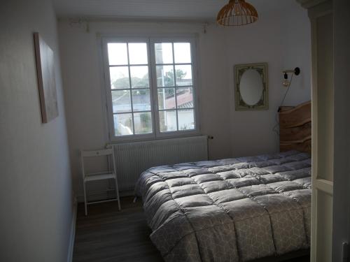 une chambre avec un grand lit et une fenêtre dans l'établissement Maison au calme proche plage, centre à 2 min à pied, à La Tranche-sur-Mer
