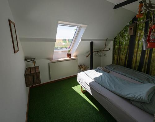 a bedroom with a bed and a window and green carpet at Holmely Bed & Breakfast in Brædstrup