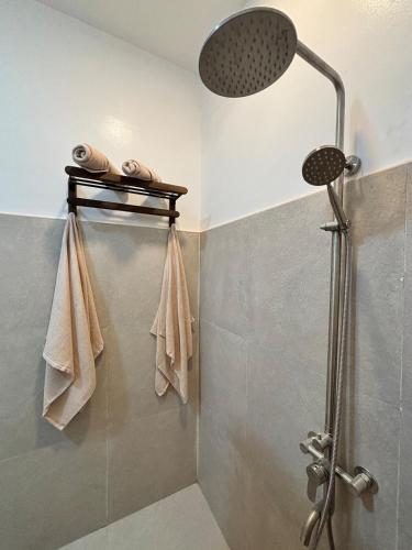 a bathroom with a shower with towels on a shelf at Casa Perla in El Nido