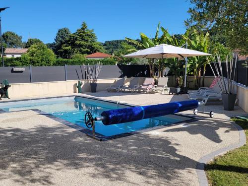 une piscine avec un grand tube bleu au milieu dans l'établissement Villa des Oliviers Sublime villa avec piscine chauffée et privée et baby foot, à Bon-Encontre