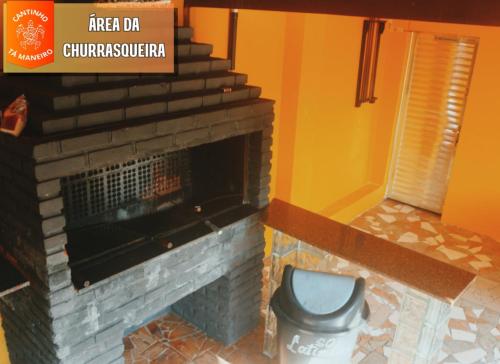 a bathroom with a fireplace and a toilet at Cantinho Tá Maneiro in Mongaguá