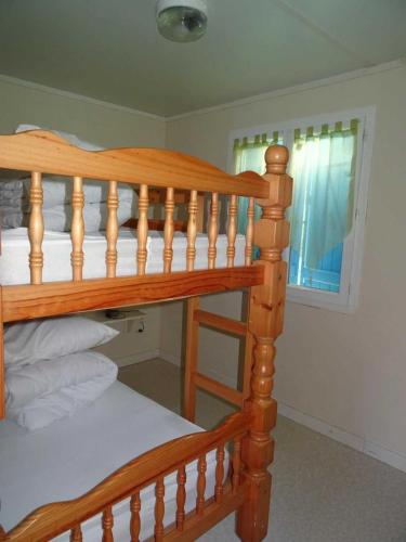 Ce lit superposé en bois se trouve dans un dortoir doté d'une fenêtre. dans l'établissement Camping 3 étoiles - Piscine - ccagi0g, à Thiviers