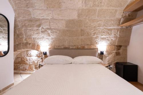 a bed in a room with a stone wall at Santo Stefano Home & Breakfast in Polignano a Mare