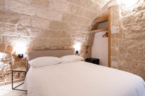 a bedroom with a bed in a stone wall at Santo Stefano Home & Breakfast in Polignano a Mare