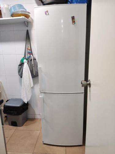 a white refrigerator in a kitchen next to a stool at Hab Moderna A 20 Minutos del Centro de Barcelona in Santa Coloma de Gramanet