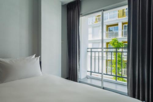a bedroom with a white bed and a window at Di Yana Patong in Patong Beach