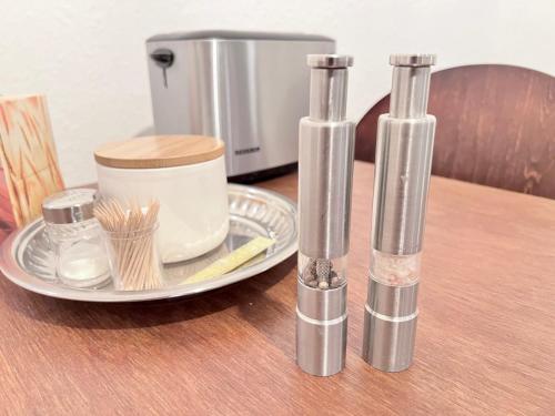 ブレーメンにあるBremen City Apartmentのコーヒーメーカーが置かれた皿の上に3つのガラスの円筒が置かれたテーブル