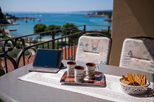 un tavolo con computer portatile e tazze di caffè su un balcone di Apartments Iva a Krk