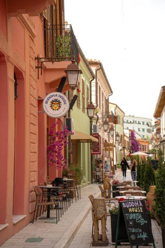 a street with tables and chairs and a clock on a building at Buddha House Hotel and Cocktail Bar in Vlorë