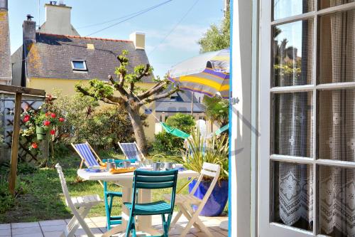 eine Terrasse mit Tisch und Stühlen und einem Fenster in der Unterkunft LocaLise - M20B - Ocean Lodge - Maison avec jardin clos - terrasse - plage à 400m - wifi inclus - draps inclus - animaux bienvenus in Le Guilvinec