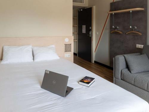 a bedroom with a bed with a laptop and a couch at Ibis Budget Saint Malo Centre in Saint Malo