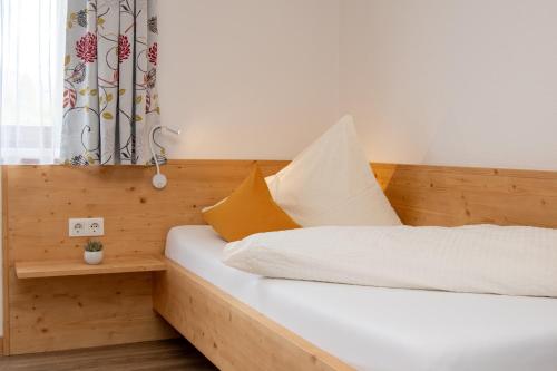 a bedroom with a bed with white sheets and yellow pillows at Gasthof-Pension Waldfriede in Liesing