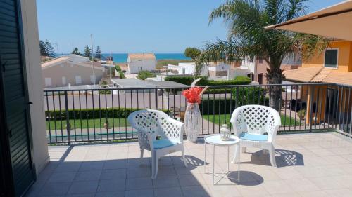 two chairs and a table on a balcony at Villa Auri in Marina di Modica