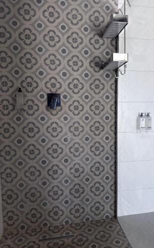 a bathroom with a shower with a tiled wall at Escapade Lux Guesthouse in Gaborone