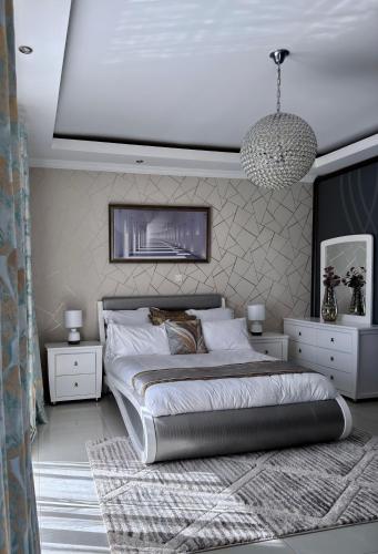 a bedroom with a large bed and white furniture at Escapade Lux Guesthouse in Gaborone