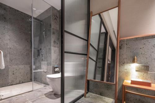 a bathroom with a toilet and a glass shower at Shanyu Life Huangshan Design Hotel in Huangshan