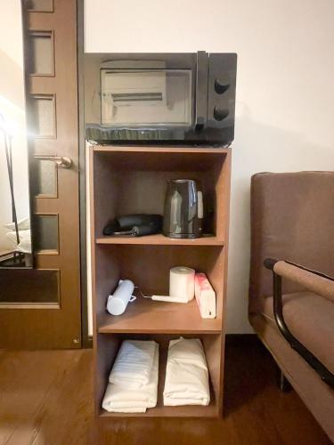 a room with a kitchen with a microwave and a cupboard at パルム天神西 in Susakiuramachi