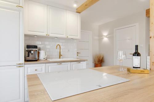 a kitchen with white cabinets and a table with a bottle of wine at Całoroczny Domek Hampton Lubniewice, jezioro, jacuzzi in Lubniewice