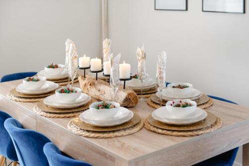 a wooden table with plates and candles on top at Całoroczny Domek Hampton Lubniewice, jezioro, jacuzzi in Lubniewice