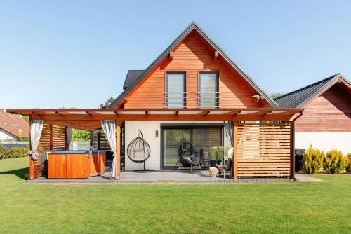 a house with a covered patio with a table at Całoroczny Domek Hampton Lubniewice, jezioro, jacuzzi in Lubniewice