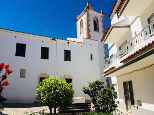 un edificio blanco con una torre de reloj en la parte superior en Paderne Village House, en Paderne