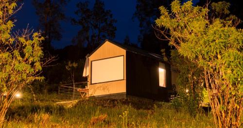 a black and white house in a field at night at Bobocabin Kawah Ijen, Banyuwangi in Biau