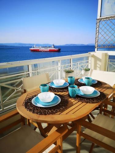 a table on a balcony with a cruise ship at Magic Sea View apartment in Rafina