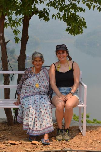 two women sitting on a bench under a tree at Mount Fuji Homestay in Deorāli