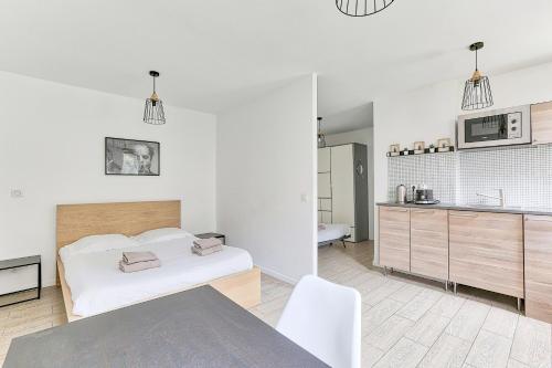 une chambre blanche avec un lit et une cuisine dans l'établissement 10 minutes à pied de La Villette - 4 voyageurs, à Paris