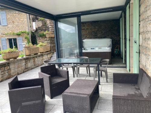d'une terrasse avec une table et des chaises en verre. dans l'établissement Gîte avec spa et piscine près de Millau, à Compeyre