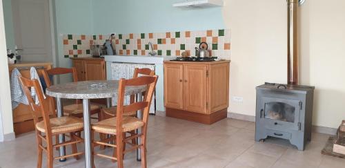 une cuisine avec une table, des chaises et une cuisinière dans l'établissement La Maison d'Onésiphore, à Cazes-Mondenard