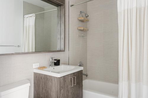 a bathroom with a sink and a tub and a mirror at Blueground Upper East Side AC wd nr parks NYC-1635 in New York