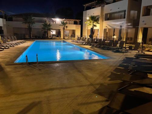 - une piscine avec des chaises et un bâtiment la nuit dans l'établissement Appartement T2 bord de mer N165, à Linguizzetta