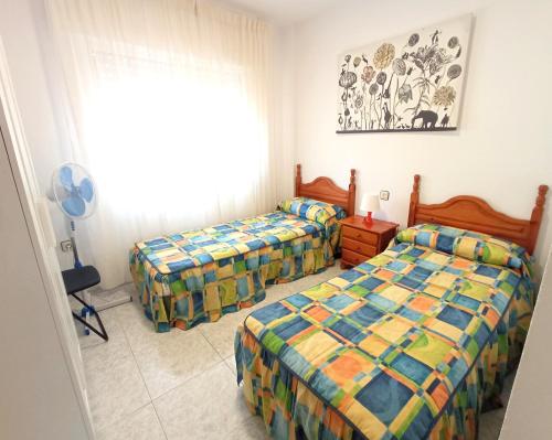 a bedroom with two beds and a window at Adosado en planta baja in Los Belones