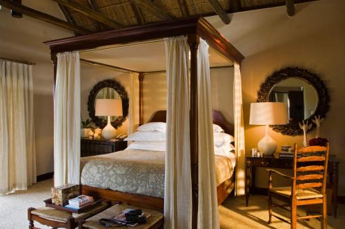 ein Schlafzimmer mit einem Himmelbett und einem Spiegel in der Unterkunft Bushmans Kloof Wilderness Reserve and Wellness Retreat in Clanwilliam