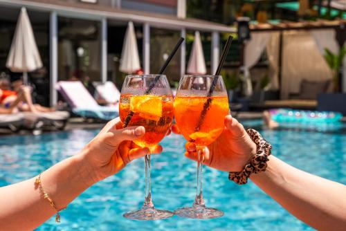 two people holding up wine glasses in front of a pool at HMA Hotel & Suites in Alanya