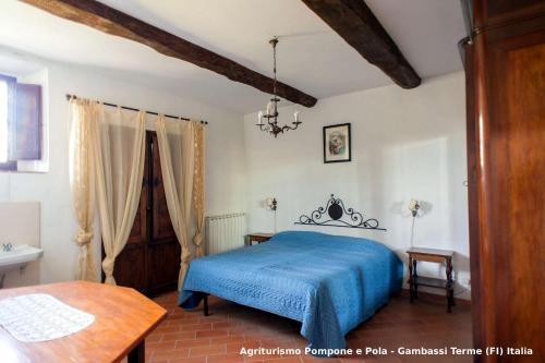 a bedroom with a blue bed and a table at Agriturismo Pompone e Pola in Gambassi Terme