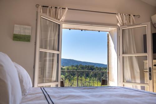 une chambre avec un lit et une grande fenêtre dans l'établissement Chez Marthe - Maison de village - Ménerbes centre, à Ménerbes