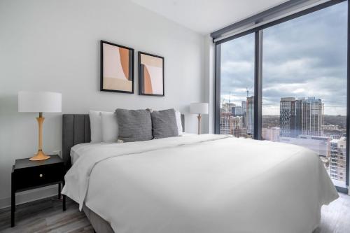 a white bedroom with a large bed and a large window at Blueground Downtown Austin pool nr Capitol ATX-235 in Austin