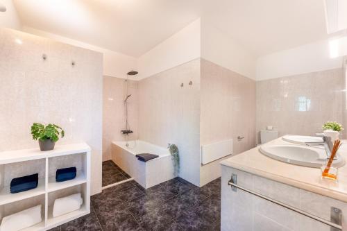 ein weißes Badezimmer mit einem Waschbecken, einer Badewanne und einer Badewanne in der Unterkunft Casa Federica by Algarve Holidays in Santa Bárbara de Nexe