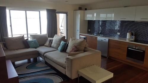 a living room with a couch and a kitchen at Villa Riviera on River Front in Ballina
