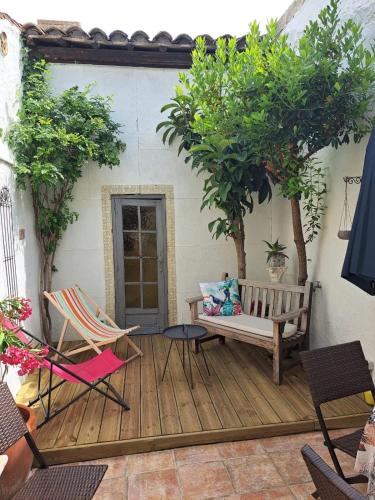 une terrasse avec un banc, une table et des chaises dans l'établissement Maison typique intra-muros, à Aigues-Mortes